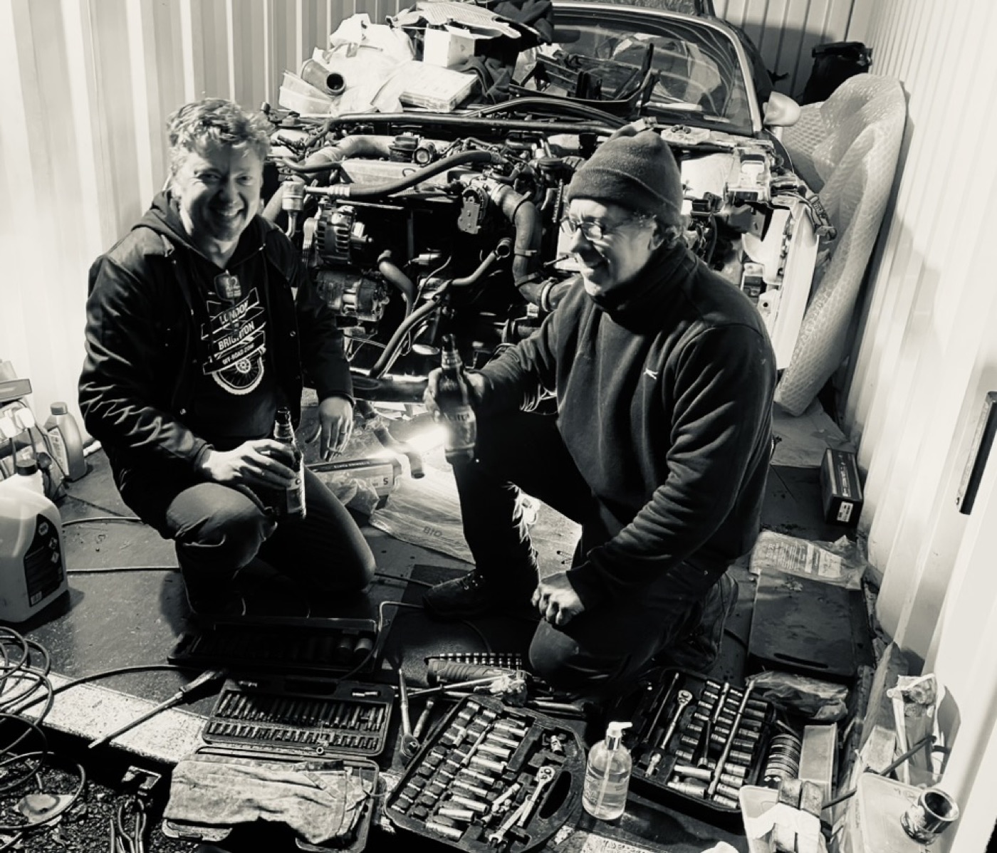 Justin James working on a car engine with a friend